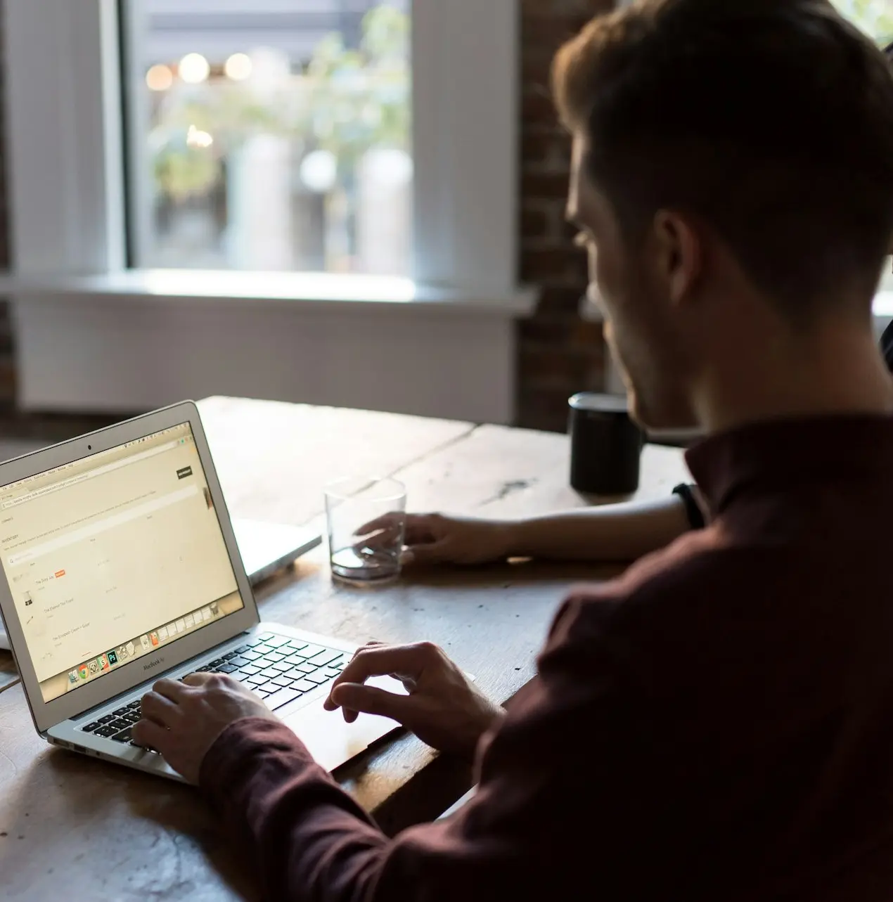man operating laptop on top of table